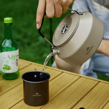 Metal pot for outdoor travel and camping cooking on a burner.
