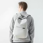 Man wearing a white travel backpack with adjustable black shoulder straps