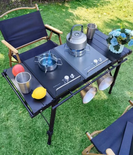 Family using an adjustable leg BBQ table for a picnic near a large family tent.
