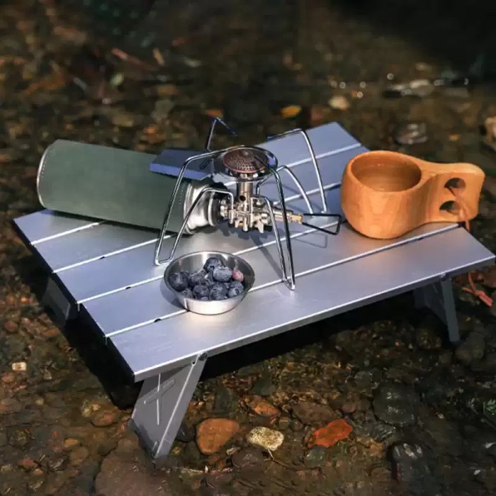A small backpacking stove placed safely on the heat-resistant surface of a mini camping table.