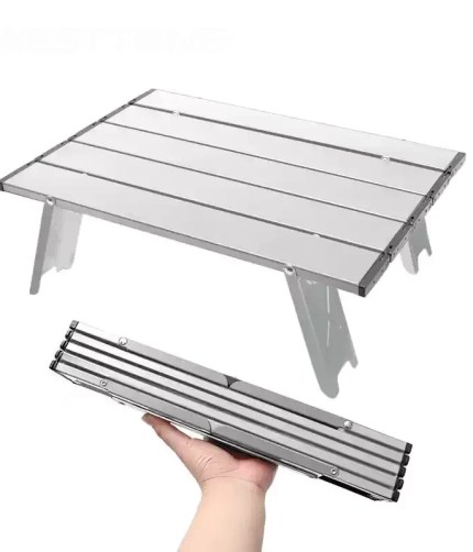 Mini camping table made of black aluminum alloy shown with a coffee mug in a mountain setting.