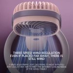 A blue mini portable fan placed on a camping table next to a tent for airflow.