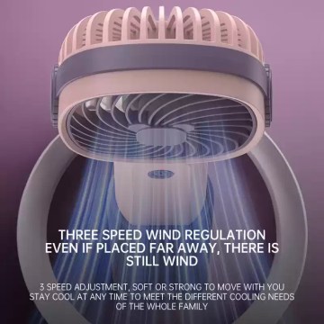 A blue mini portable fan placed on a camping table next to a tent for airflow.