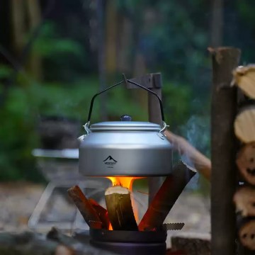 Camping kettle on stove over fire for outdoor cooking