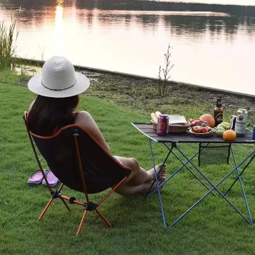 Folding moon Camping chair and table setup by lakeside