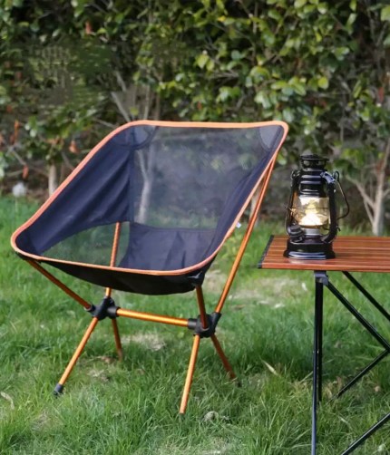 Lightweight aluminium folding camping chair with lazy back moon design placed on grass, portable outdoor chair suitable for camping, festivals and garden use