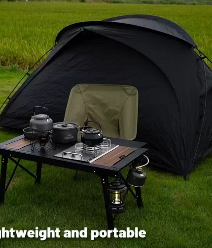 Black aluminum alloy table with adjustable lifting legs shown in a woodland camping setup.