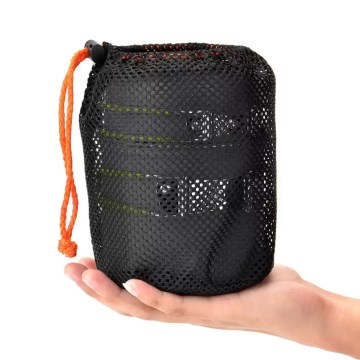 The ultralight outdoor tableware set inside its mesh carry bag being held to show its compact size.