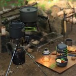 A complete outdoor cooking setup featuring the cookware kit, a camping kettle, and a folding table.