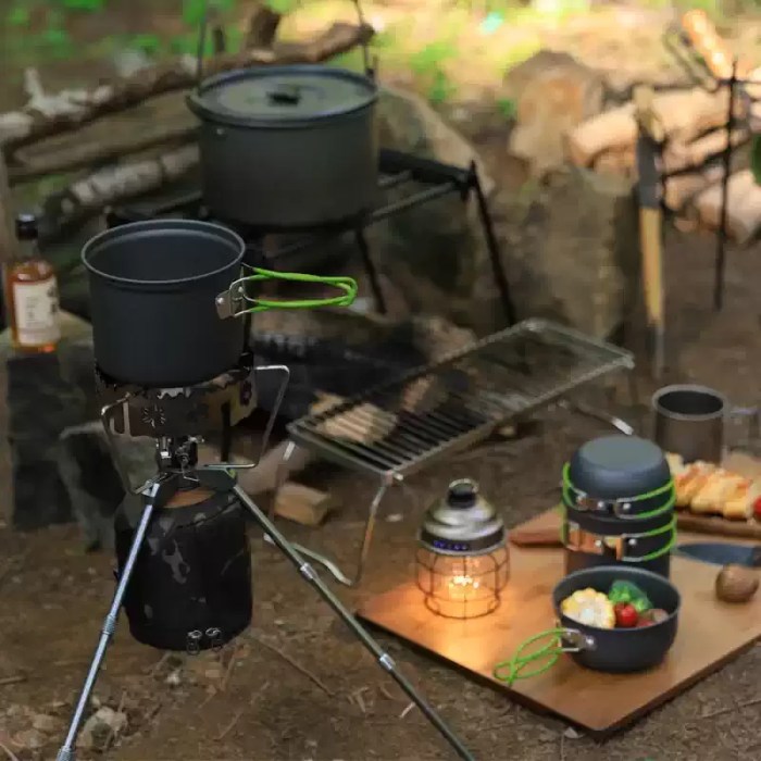 A complete outdoor cooking setup featuring the cookware kit, a camping kettle, and a folding table.