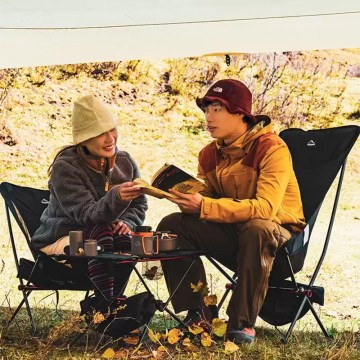 Couple relaxing on folding camping chairs during outdoor camping