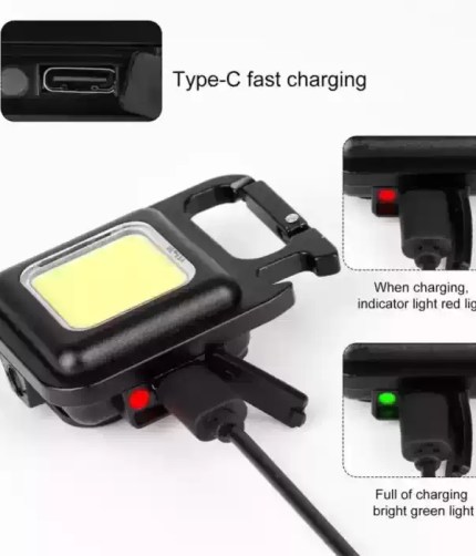 A compact black super bright mini COB keychain flashlight connected to a charging cable, showing a red indicator light during charging and a bright green light when fully charged.
