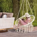 Hand-woven cotton rope hanging chair in a natural cream color suspended in a garden.