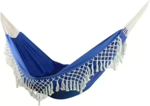 Blue double enlarged canvas hammock with retro tassels hanging between two trees.