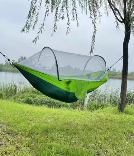 A hiker sleeping securely inside the bug-proof hanging bed during a nature hike.