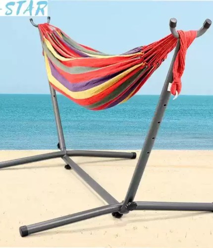 Outdoor camping portable single hammock with a black metal folding frame in a green garden.