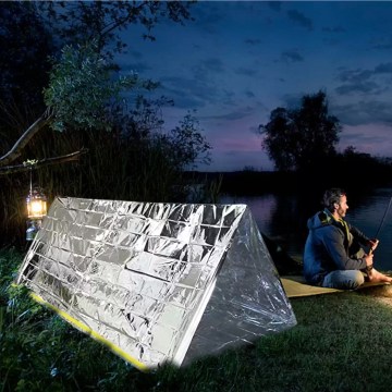 Hikers using a waterproof emergency shelter with a Mylar blanket during a storm.