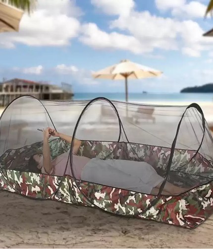 1-2 person camping mesh tent set up in a green forest for summer hiking.