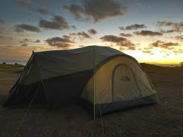 A camping tent set up in a scenic outdoor location during sunset, showcasing its spacious design and color.