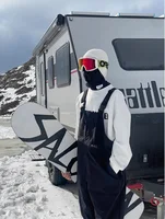 Black Snowboard Bib Side View Side view of black insulated snowboard bib trousers beside a mountain vehicle