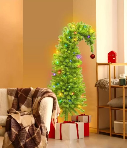 Pre-lit bent top artificial Christmas tree in cozy living room.