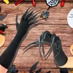 Long black claw costume gloves on Halloween decorated background