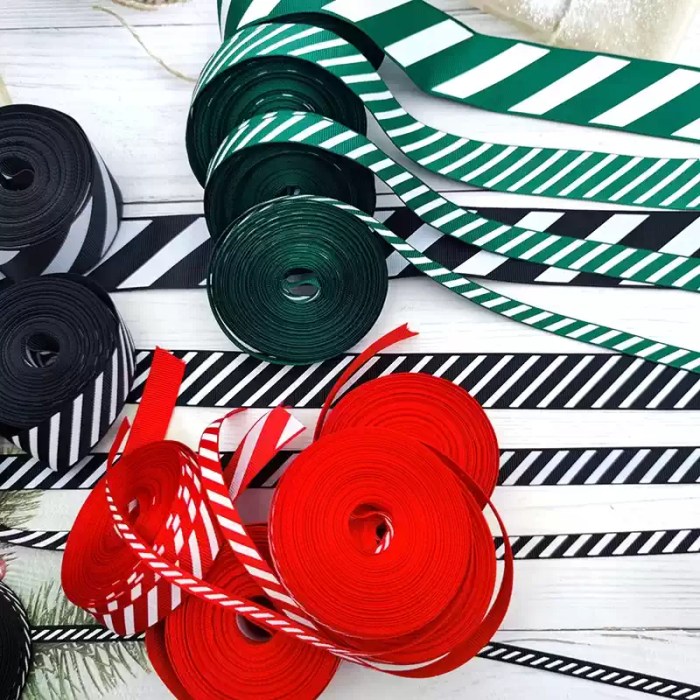 Assorted rolls of red, green, and black candy cane striped grosgrain ribbons displayed on a light background.