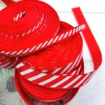 Stacked spools of red and white diagonal striped grosgrain ribbon up close.