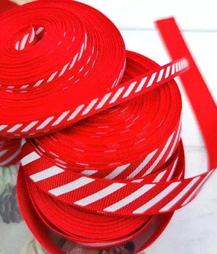 Stacked spools of red and white diagonal striped grosgrain ribbon up close.