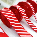 Rolls of red and white candy cane striped grosgrain ribbon lined up on a white surface.