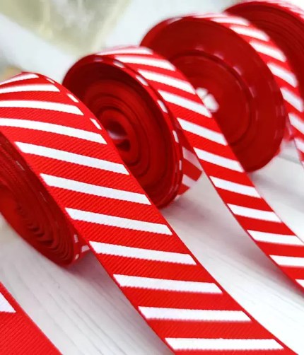 Rolls of red and white candy cane striped grosgrain ribbon lined up on a white surface.