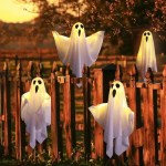 White LED glowing ghost decorations hanging on a wooden garden fence.