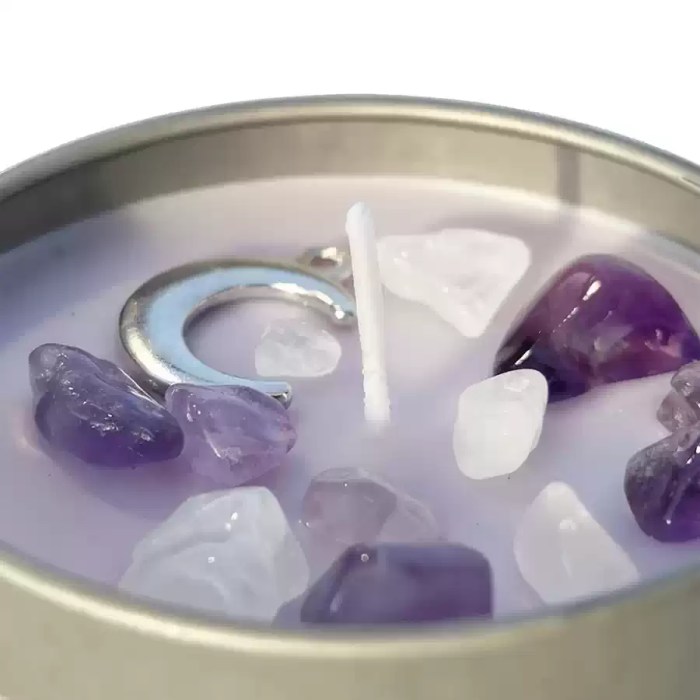 Close-up of purple soy wax candle decorated with purple and white crystal stones around the wick.