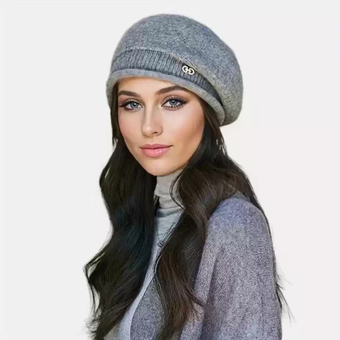 Grey Knitted Slouchy Beanie Hat Grey knitted slouchy beanie hat featuring a ribbed band and a small metallic logo detail worn by a model.