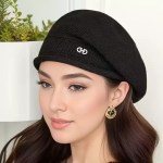 Black knitted slouchy beanie hat styled with a structured ribbed brim and a polished center logo emblem.