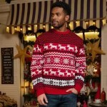 Man standing with hand in pocket wearing a red knit holiday sweater.