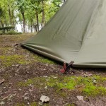 The Ultra Stove Tent with a wood stove chimney venting through the roof in a snowy camp.