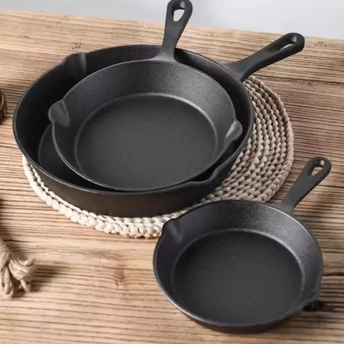 A cast iron frying pan being used as an omelette pan on a modern induction cooktop.