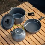 Heat-resistant folding handles on a portable pan set for safe cooking over campsite gas burners.