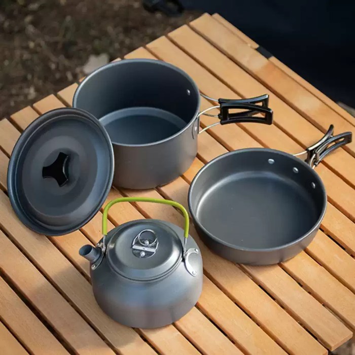 Heat-resistant folding handles on a portable pan set for safe cooking over campsite gas burners.