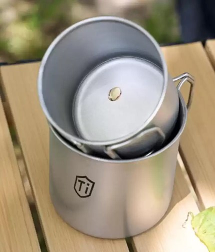 Premium titanium mug used by a solo hiker for a morning coffee at a wild camp spot.