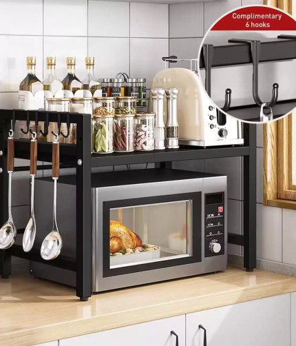 Two-tier expandable microwave oven rack with complimentary hanging hooks organizing kitchen supplies and spices.