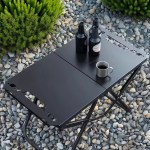 Top-down view of the black tactical table set up on a rocky outdoor surface with a coffee mug and bottles.
