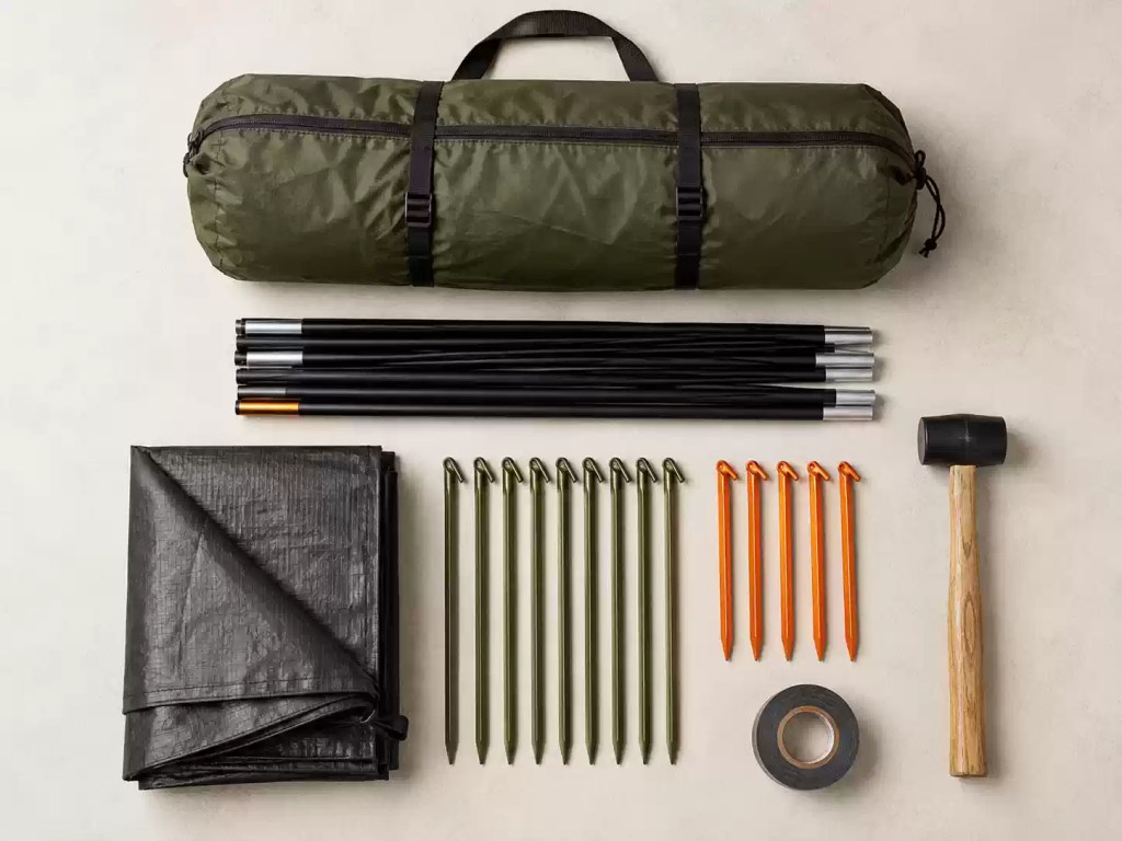 Festival sleeping setup inside a tent with sleeping mat, sleeping bag, pillow, lantern and organised camping bag
