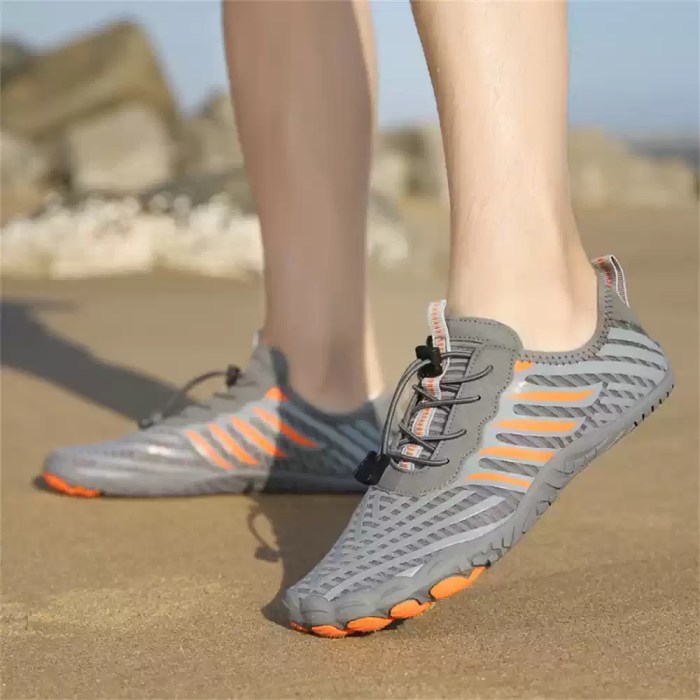 Close-up of comfortable grey and orange water shoes worn on a rocky beach.