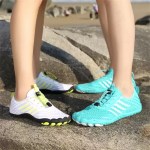 Two people wearing white and teal quick-dry water shoes while standing on coastal rocks.