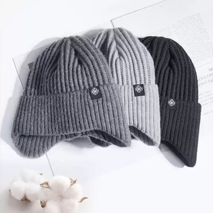 Winter Beanie Color Options Collection Three winter knit beanies with ear flaps displayed side by side in dark grey, light grey, and black color variations with a decorative snowflake brand tag