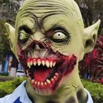 Green zombie Halloween mask with bulging eyes and sharp teeth