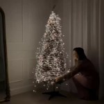 Flocked Christmas tree setup with illuminated foldable branches.