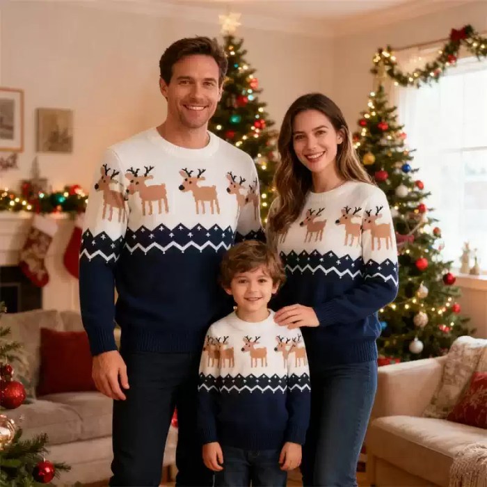 matching-navy-blue-family-reindeer-sweaters arents with their young son indoors wearing matching navy blue and white reindeer Christmas sweaters.